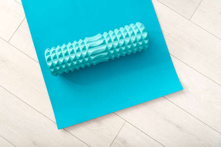 Blue foam myofascial roller. Tools for self-massage on blue yoga mat. Equipment for MFR. Top view.の写真素材