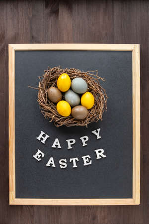 Multicolored Easter eggs and the inscription Happy easter in frame on black backgroundの写真素材