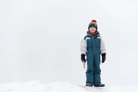 Boy plays outside during snowfall. Winter holidays. Child walks outdoors in winter
