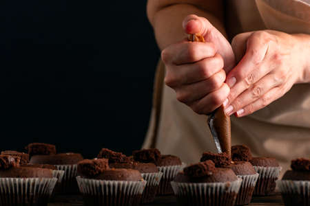 Chef fills the cupcakes with chocolate cream from the confectionery bag. Process of making muffins....