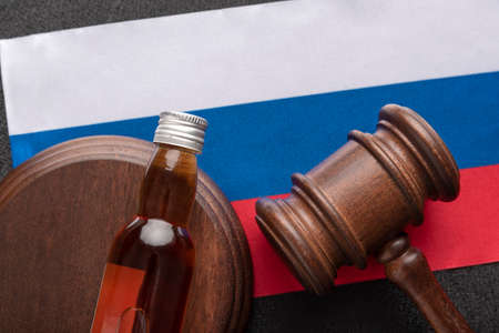 Judge gavel and bottle of alcohol on flag of Russia background. Law on alcohol in Russia. Concept alcohol and conflicts with the lawの写真素材