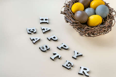 Colorful Easter eggs in birds nest and Happy easter lettering on gray background.の写真素材
