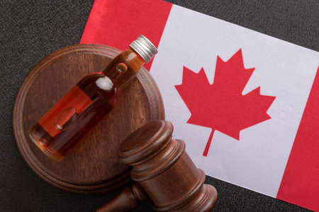Bottle of alcohol and wooden gavel as symbol of law and flag of Canada. alcohol and crime conceptの写真素材