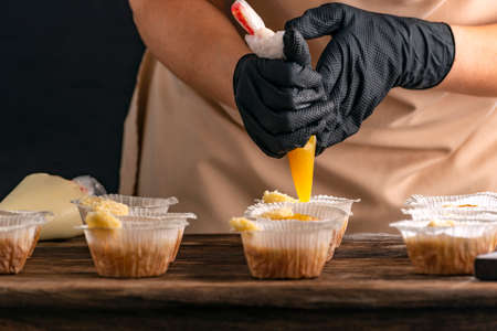 Pastry chef fills muffins with jam. Process of making cupcake by handの写真素材