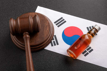 Wooden gavel and Bottle of alcohol as symbol of law on Korean Empire flag. alcohol lawsuit conceptの写真素材