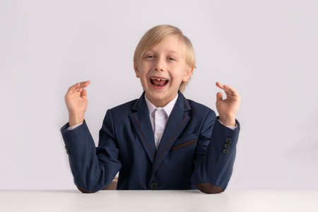fidget boy. Blond boy in school uniform fools around and laughs. Portrait of primary school child