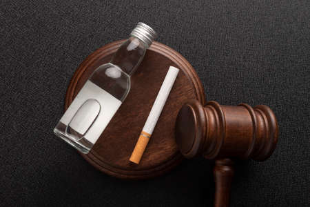 Judge gavel next to cigarettes and bottle of alcohol. Alcohol and Tobacco Law.Top view.の写真素材