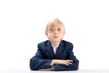 Portrait of blond schoolboy on white background.Elementary school student wears glasses sit idly by...