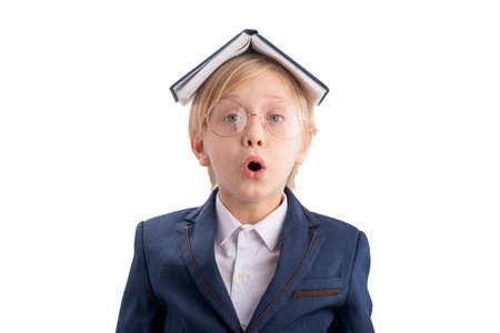 Surprised boy holding book as house above his head. Caucasian kid fooling around. Schoolboy portrait isolated on white backgroundの写真素材
