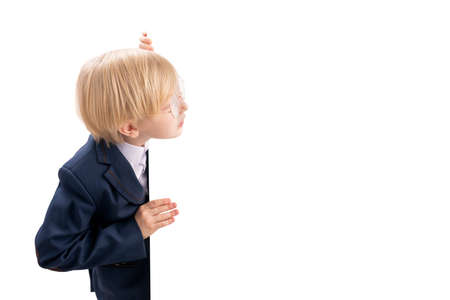 Boy in school uniform peeks out from white board. Schoolboy isolated on white background. Place for your text. copyspace.の写真素材