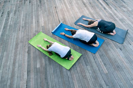 Group of young women is practicing yoga outdoors. Balasans. Yoga child pose. top viewの写真素材