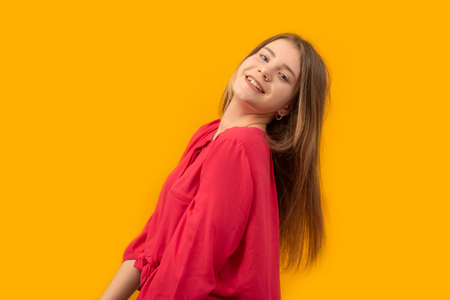 Portrait of a young girl laughing and looking into the camera. Young woman in red shirt on an yellow...