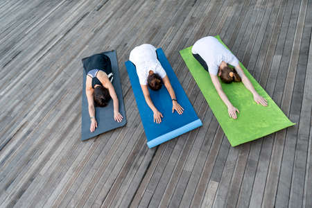 Group of young women is practicing yoga outdoors. Yoga child pose. Balasana.Top view.
