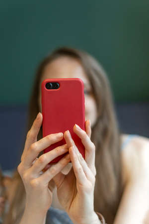 Women's hands hold smartphone. Girl takes selfie or talks to someone on video call. vertical frameの写真素材