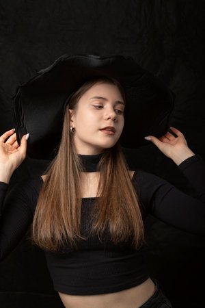 Portrait of beautiful girl in black top and wide-brimmed hat. Stylish young lady. vertical frame