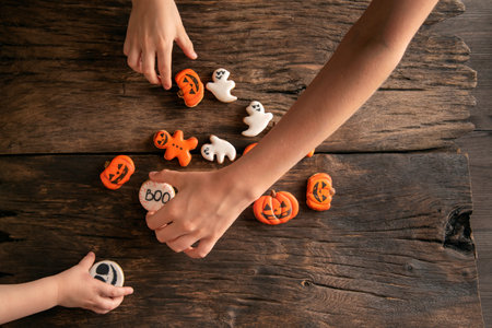 Festive gingerbread on halloween in form of pumpkins, ghosts and ginger man in childrens hands on wooden background. top viewの写真素材