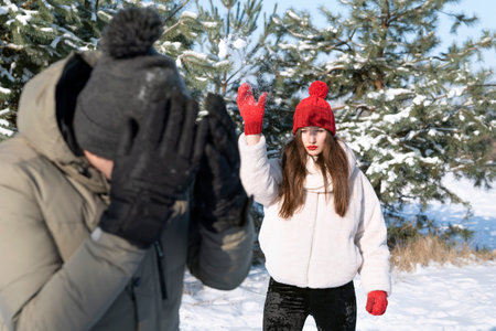 Young woman and boy are playing snowballs in winter forest. friendships, relationships. winter holidays.の写真素材