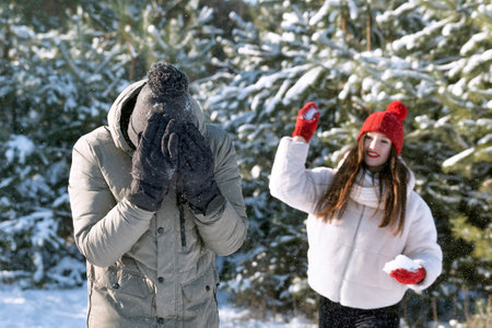 Guy and girl are playing snowballs in the forest. friendships, relationships. winter holidays.の写真素材