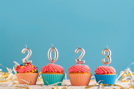 Festive cupcakes and silver candles in form of numbers 2023 on blue background. concept of new yearの写真素材