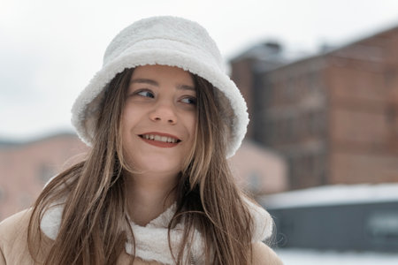 Close-up portrait of smiling girl in fashionable white fur panama in winter outdoors. Woman in trendy headdress.の写真素材