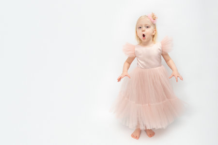 Little girl with surprised face. Cute girl in elegant lush dress and bare feet isolated on white background. copyspace.の写真素材