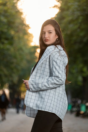 Portrait of beautiful young brunette woman in plaid shirt in the park. student girl walking in the parkの写真素材