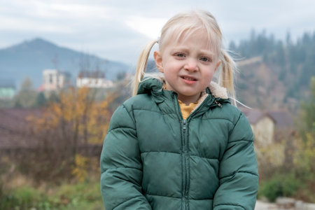 Portrait of little blonde girl with two tails and red nous standing in fresh air of the countryside. vacation in autumnの写真素材