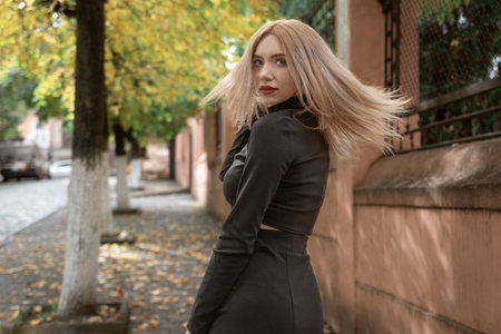 Young beautiful woman with blonde hair walks around the autumn city. Girl turns around and looks into the cameraの写真素材