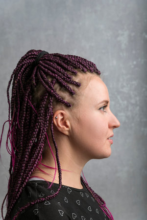 Profile portrait of a young woman with pigtails on gray background. Vertical frame.Informal freaky girl wears dreadlocks.の写真素材