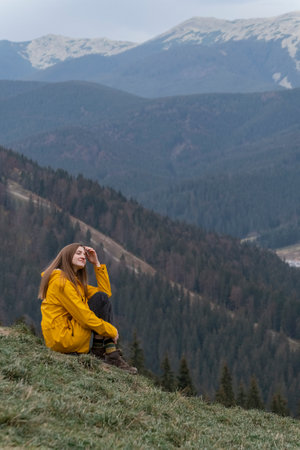 Portrait of young happy woman in mountains enjoying clean air and nature. Girl sits on the side of the mountain. vertical viewの写真素材