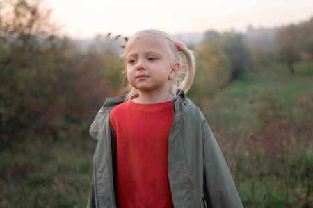 Portrait of little four-years blond girl with two tails on autumn landscape background. Child girl...
