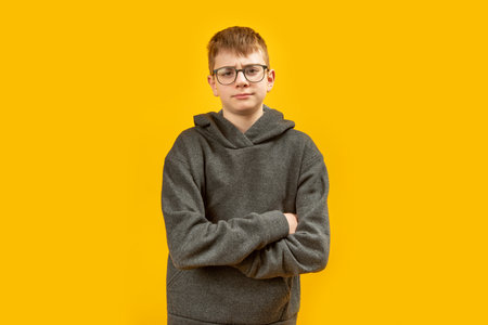Portrait of teenage boy in oversized hoodies and glasses crossed his arms across his chest and frowned. Awkward age guys. copy spaceの写真素材