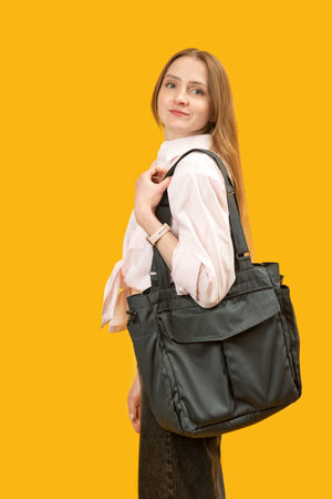 Portrait of woman with black textile shopping bag on yellow background. girl after shopping. vertical frameの写真素材