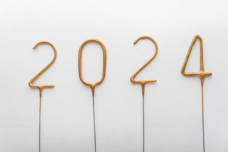 Numbers of year 2024 made from golden sparklers on white background. Celebrating New Year, close-upの写真素材