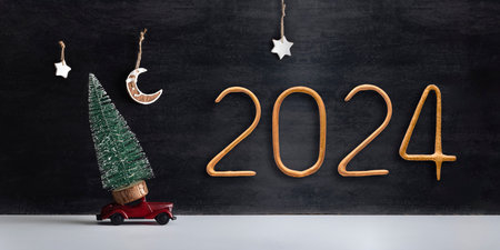 Small tree stands on model car and golden number 2024 on black background. Round-the-clock delivery for the new year.の写真素材