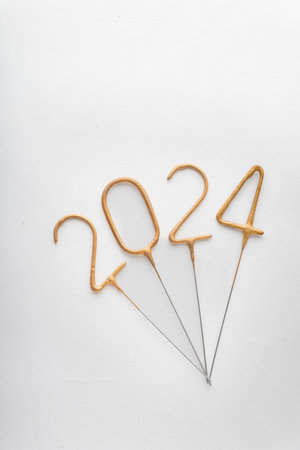 Numbers of year 2024 made from golden sparklers on white background. Vertical frame. Celebrating New Year, close-up.の写真素材