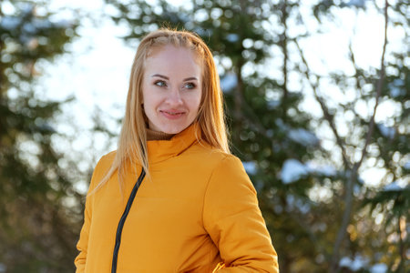 Portrait of a young woman in a yellow jacket in the park