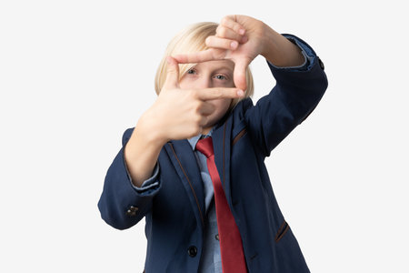 Portrait of a boy making a frame with his fingers on white background.の写真素材