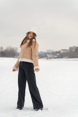 Beautiful young girl in a winter park on a background of snow.の写真素材