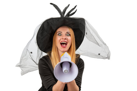 Smiling woman wearing a witch costume is shouting through a megaphone for Halloween parties.の写真素材