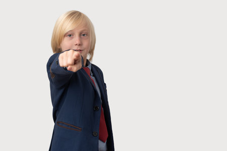 Little boy in a business suit points a finger at the cameraの写真素材