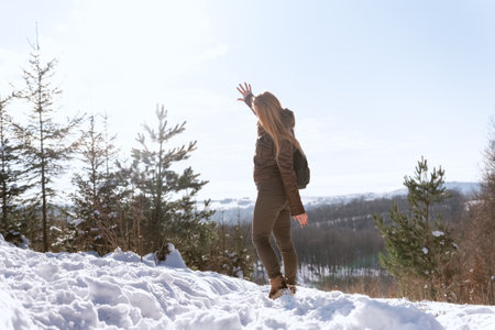 A young woman in a brown coat walks through the winter forest