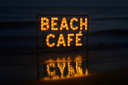 Illuminated beach cafe sign reflecting on the wet sand at night, creating a warm and inviting atmosphereの素材
