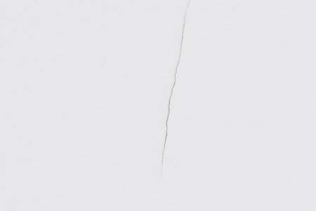 Close up of a long, thin crack running vertically down a pristine white surface, creating a stark contrast and suggesting structural damage or stressの素材
