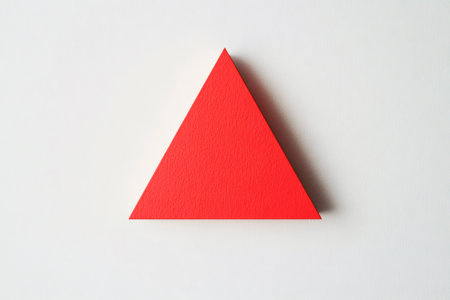Minimalist image of a red triangle casting a subtle shadow on a textured white background, creating a simple yet striking visualの素材