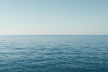 Calm ocean water surface meeting clear blue sky in a minimalist composition, during a serene daytimeの素材