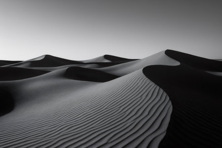 Windswept sand dunes form mesmerizing patterns across a vast monochrome desert landscape, showing the beauty of nature's artistryの素材