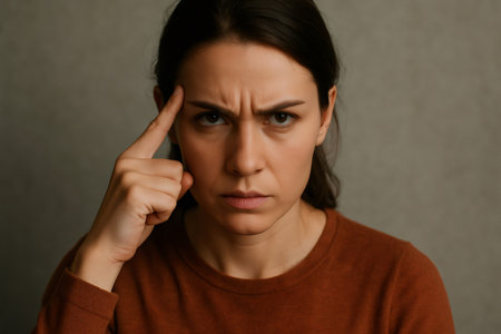 Woman pointing finger to her temple, symbolizing deep thought, concentration, and problem solvingの素材