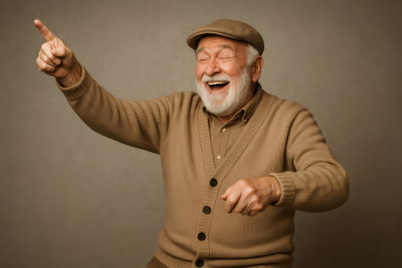 Elderly man with white beard wearing casual clothes portraying a joyful mime, pointing his finger and laughing on neutral backgroundの素材