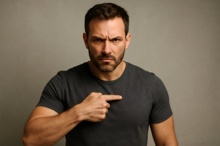 Portrait of a serious man pointing his finger at himself, conveying a sense of responsibility or self identificationの素材